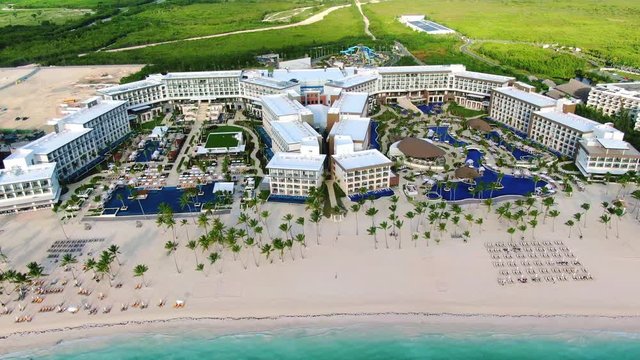 Luxury hotel on tropical island, white sand beach with palm trees and turquoise blue ocean, exotic vacation getaway, indyllic aerial panoramic scene