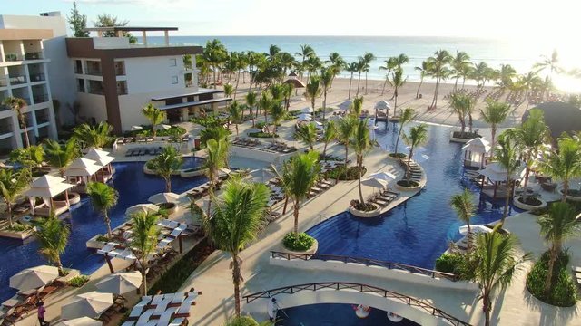 Infinity pool in tropical resort, lounge chairs and umbrellas under palm trees, aerial perspective of Caribbean travel destination, sand beach and ocean view, paradise seascape in Dominican Republic