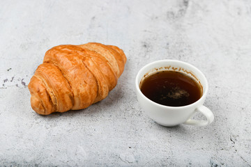 croissant and cup. on a specific background. Fresh french croissant. on a wooden background. View from above. Morning breakfast with a croissant. A French breakfast is prepared at home. on the stove a