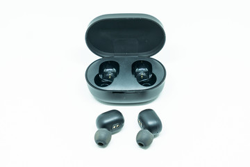 Close up of wireless earphones and the charging case, isolated on white background.