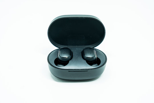 Close up of wireless earphones on the case, isolated on white background.