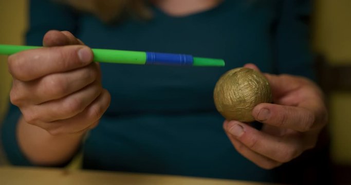 Young woman decorating easter egg with golden paper