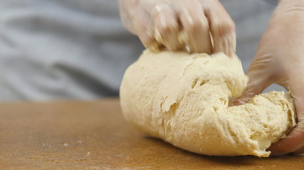 woman mother or daughter on the kitchen table makes domestic food pizza, hands work and pushing stir knead the dough, selective focus dolly shot