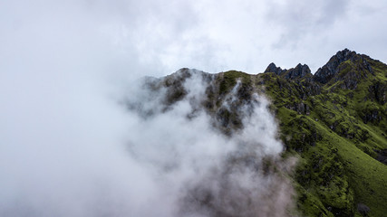 Aerial view of high green mountains rocky peaks covered with fog and clouds  at very high altitude in Peruvian Andes close to Pisac, Cusco. 