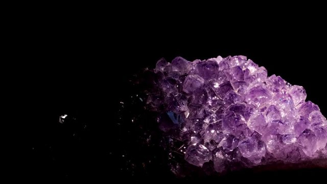 Seamlessly rotating a purple mineral (Amethyst) in front of black background.