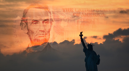 Statue of Liberty in silhouette with a portion of a warm-toned five-dollar bill in the horizon...