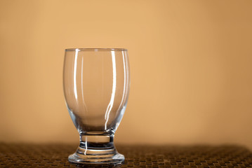 Una copa de vino transparente de vidrio vacia sobre una mesa texturizada y un fondo color beige