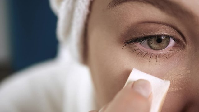 Girl applying concealer on face. Macro shot of attractive woman who is painting skin under her eyes with concealer cream. Make-up artist, beauty, body care, preparation of date or celebration concept