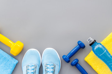 Athletics accessories. Dumbbells, towel, sneakers on grey background top-down copy space