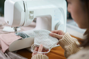 Woman using the sewing machine to sew the face mask during the coronavirus pandemia.