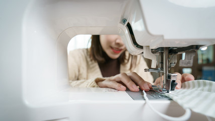 Fototapeta premium Woman using the sewing machine to sew the face mask during the coronavirus pandemia.