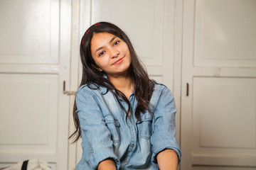 Hispanic young man in his room with white closet in the background - woman smiling at the camera