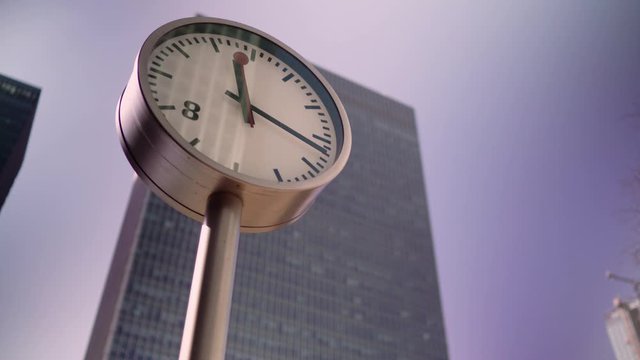 London Canary Wharf clock in front of a big skyscraper building during daytime as the seconds and minute pass in a sunny day