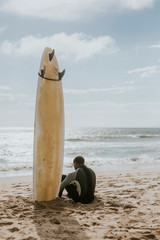 Surfer resting on the beach - obrazy, fototapety, plakaty