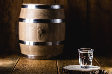 Old rustic oak barrel and glasses of high quality distilled alcohol. Brazilian silver cachaça,...