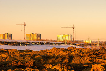 pile of excavated soil for leveling the relief in the distance multi-storey buildings are being built using tower cranes