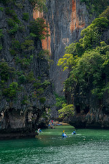 Tourists kayaking in emerald color sea to limestone islands in Phang-nga Bay national park near Phuket Thailand. A famouse activity for summer vacation.