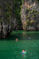 Tourists kayaking in emerald color sea to limestone islands in Phang-nga Bay national park near Phuket Thailand. A famouse activity for summer vacation.