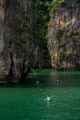 Fototapeta na wymiar Tourists kayaking in emerald color sea to limestone islands in Phang-nga Bay national park near Phuket Thailand. A famouse activity for summer vacation.
