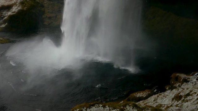 Tilt up view of Seljalandsfoss waterfall in Iceland from behind