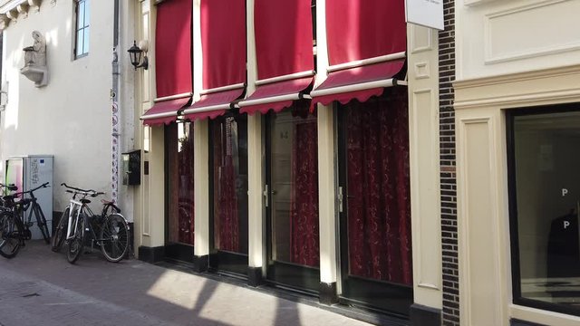 Slow pan left to right of four windows in the red-light district with a strong wind blowing its curtains in De Wallen, Amsterdam