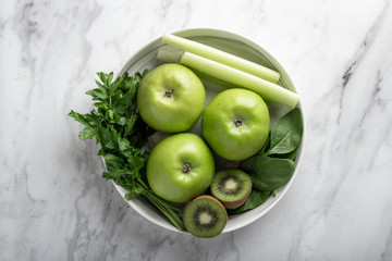 Green fruits and vegetables for making detox smoothie. Apples, kiwi, spinach, celery and parsley on a light background. Top view.