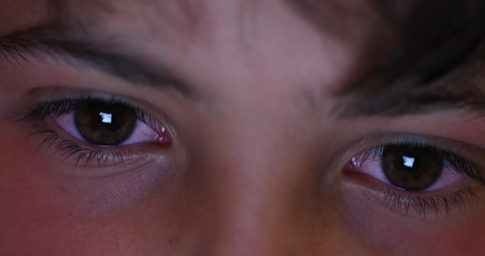 Young boy eyes macro close-up of eyes. Child eye staring at scren device at night