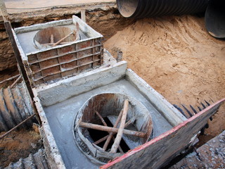 Wooden foundation formwork for concrete foundations Construction of a city sewerage system on a paved road background. Selective focus
