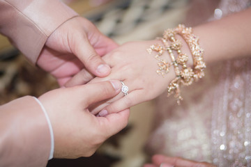 groom wears ring on bride's finger in wedding ceremony