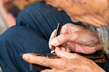 An old man is carving on a bamboo board

