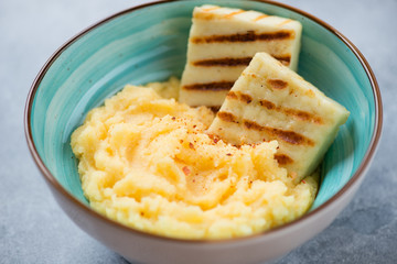 Close-up of a turquoise bowl with polenta and roasted cheese, selective focus