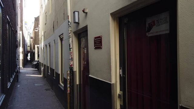 Slow pan right to left in a narrow street of the red-light district in De Wallen, Amsterdam, during daytime