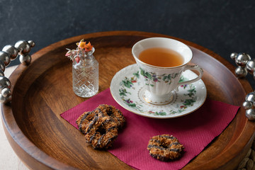 Hot tea in a beautiful cup with coconut chocolate cookies on a wooden round tray