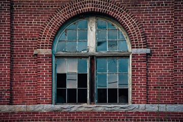 Arch broken glass window on brick wall