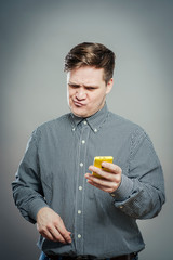 A confused young man looking at mobile phone