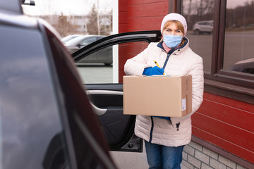 Obraz na płótnie Canvas Delivery man holding cardboard boxes in medical rubber gloves.