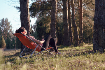 Woman relaxing in deckchair in nature in sunset.
