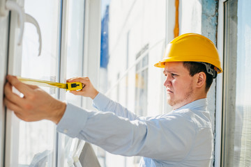 young engineer in a helmet metr the window