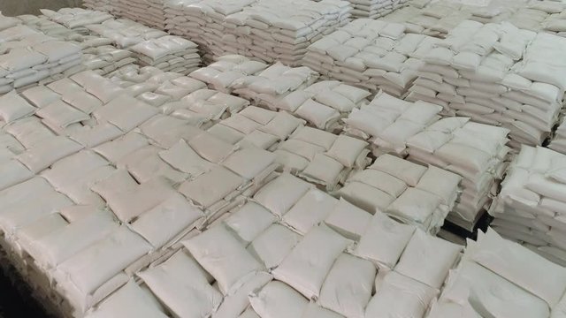 Top view of stacked white sacks stored inside a large warehouse showing a large volume of products for wholesale level distribution.