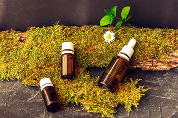 Essential oil in bottles unbranded blank packages on black background. Aromatherapy and natural...