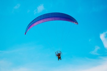Aircraft parachute with a motor. Man with paraglider fly in the blue sky.
