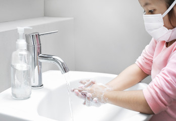 Girl child washing hands with soap warm water, rubbing nails and fingers washing frequently or...