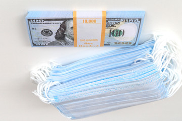 Blue medical masks, and american money.High price of masks and demand during quarantine in United States, Europe and global pandemic. Pile of anti virus surgical face masks and money. Concept.