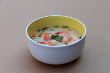 Rice congee mixed with shrimp in the round bowl. Sprinkled with spring onions and coriander.
