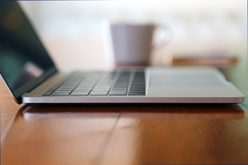 Nomad working concept, Laptop on wooden table with cup of hot coffee  and smartphone behind. Working remotely concept.