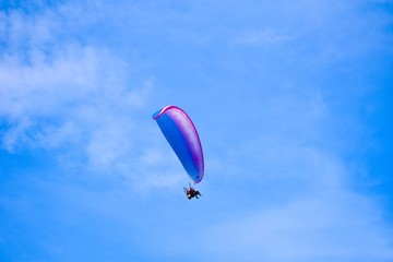 Aircraft parachute with a motor. Man with paraglider fly in the blue sky.