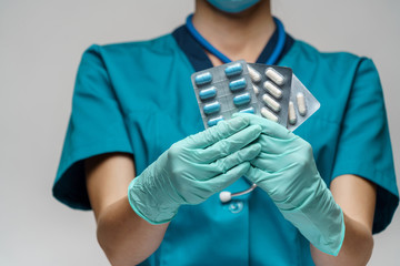 medical doctor nurse woman wearing protective mask and rubber or latex gloves - holding blisters of pills