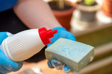 hands in blue gloves pour liquid on a sponge