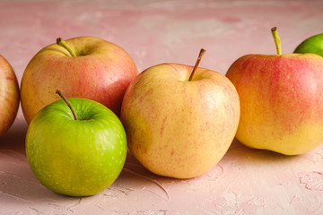 Fresh sweet apples on pink textured background, angle view macro