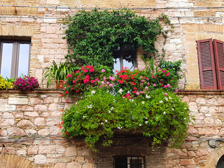 Obraz na płótnie Canvas Colorful flowers on the balcony of an ancient, stone house in Italy.